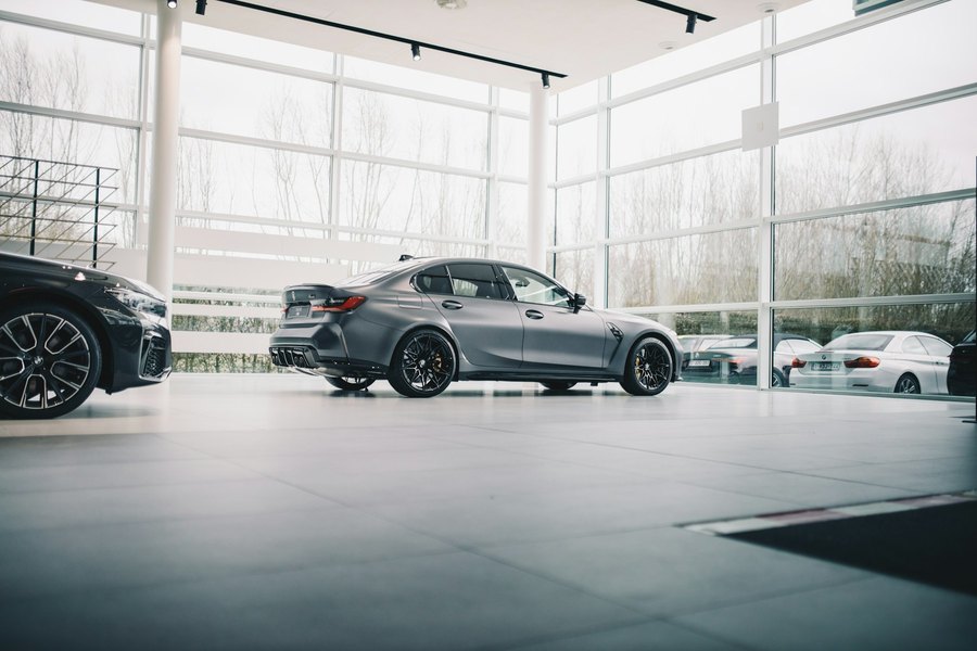 Sedan on a polished showroom floor beside a floor-to-ceiling glass wall