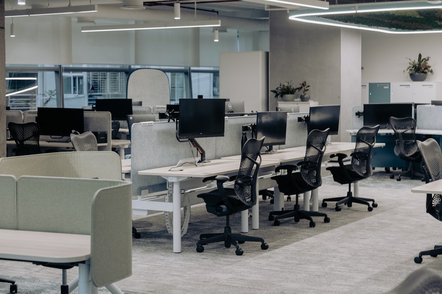 Rows of height-adjustable desks and mesh chairs in an open-plan office