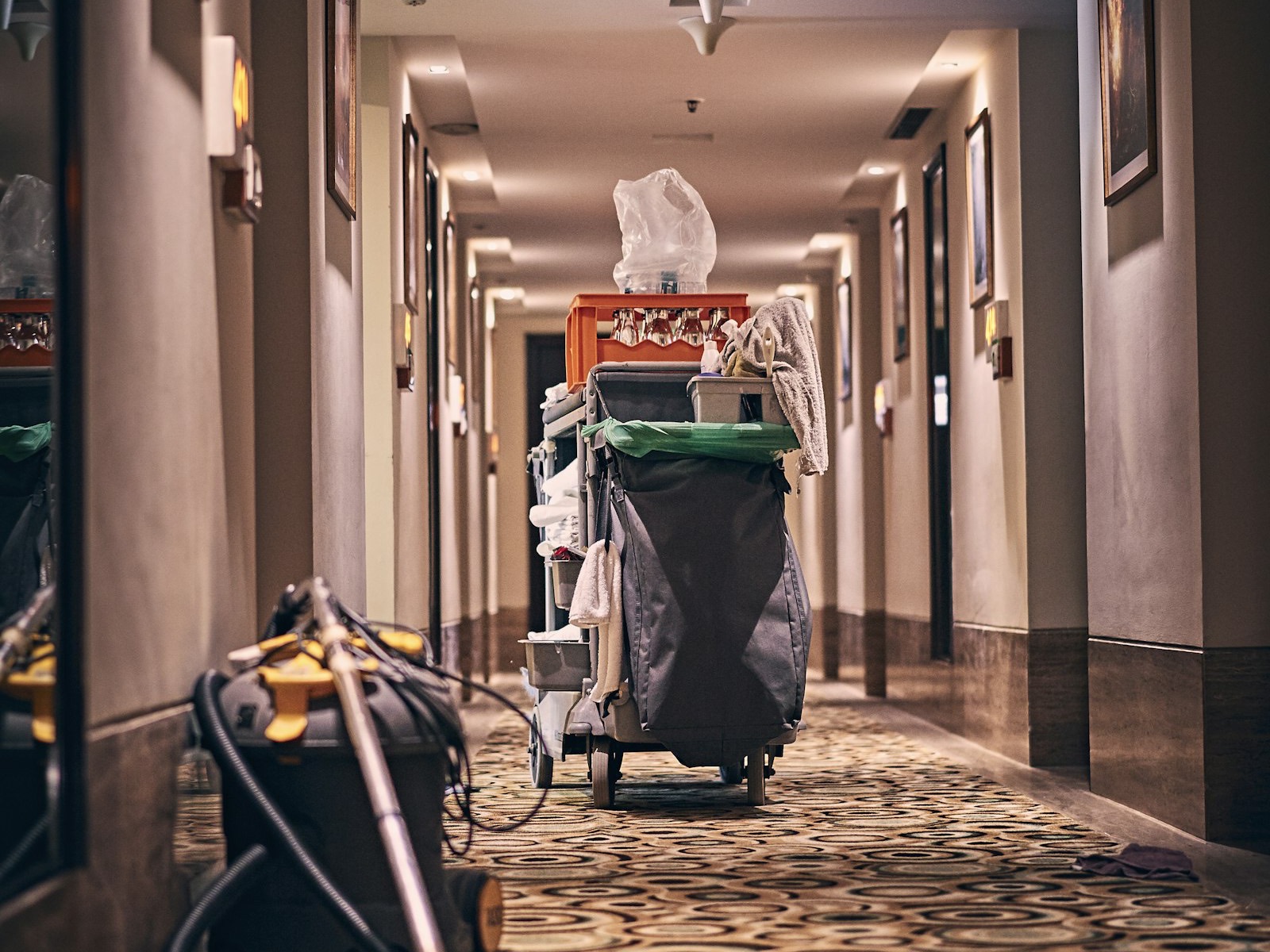 Housekeeping cart and vacuum in a carpeted hotel corridor