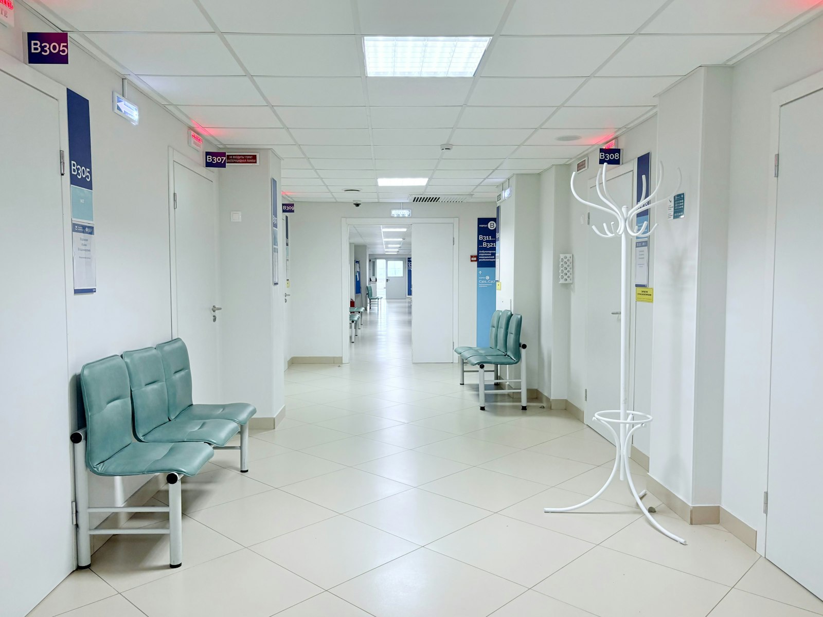 Empty hospital corridor with benches and numbered doors