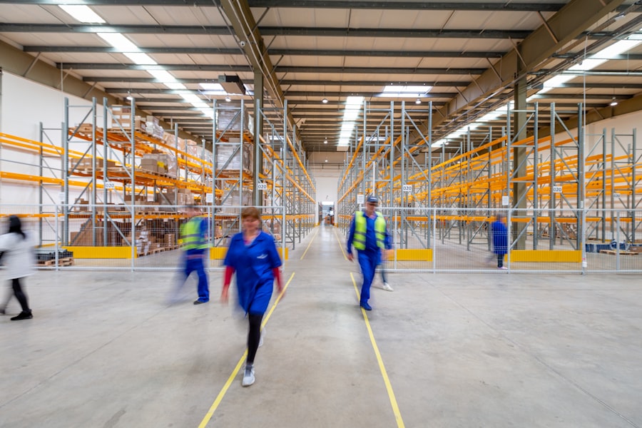 Workers crossing a large warehouse floor between orange racks