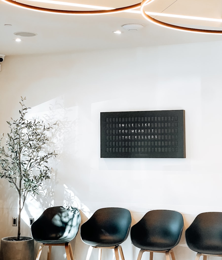 Medical office waiting room with a row of black chairs beneath a wall sign