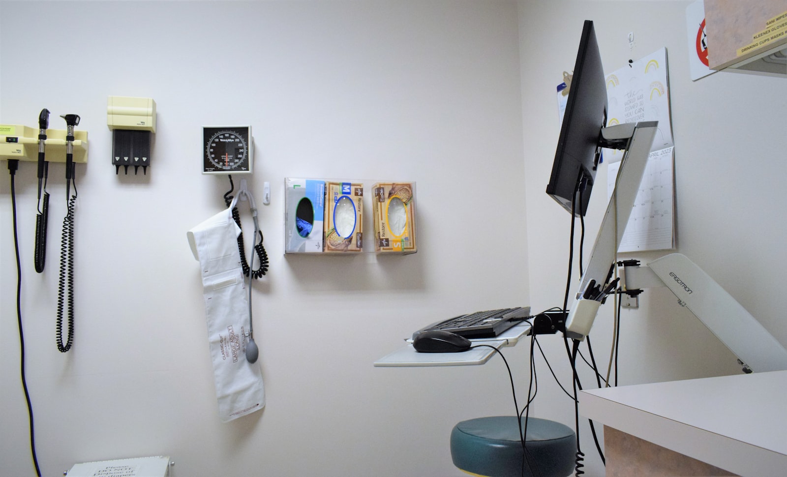 Exam room wall with diagnostic instruments and a monitor arm