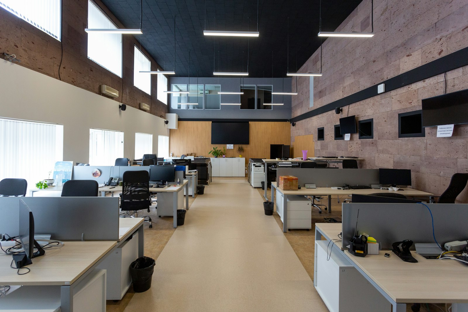 Open-plan office with rows of desks under linear ceiling lights