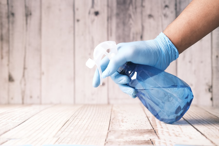 Gloved hand spraying disinfectant on a wooden surface