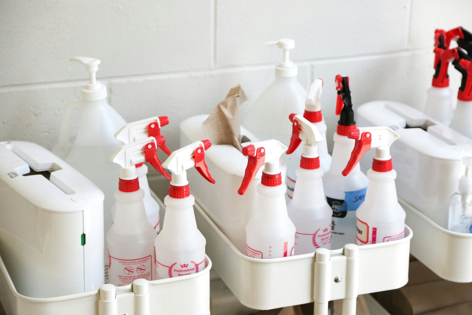 Spray bottles, soap dispensers and paper stock staged in supply caddies