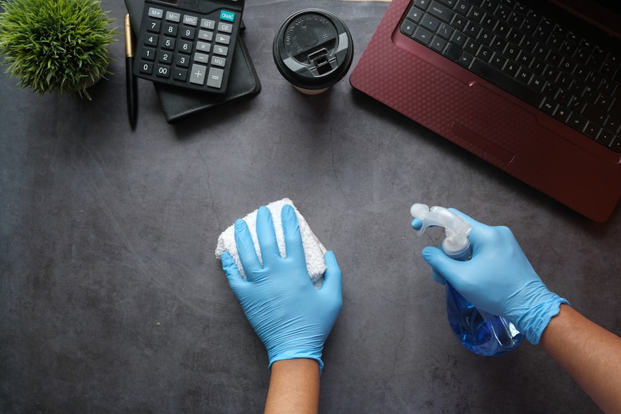 Gloved hands wiping a desk with spray and cloth