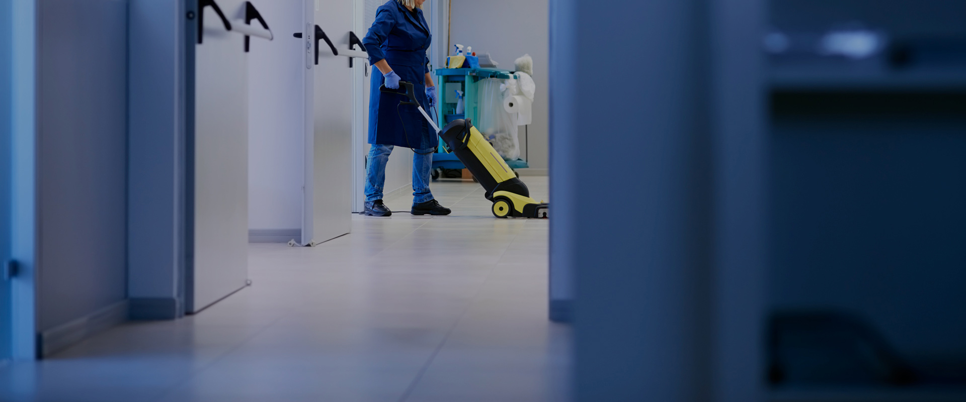 Cleaner vacuuming an office corridor